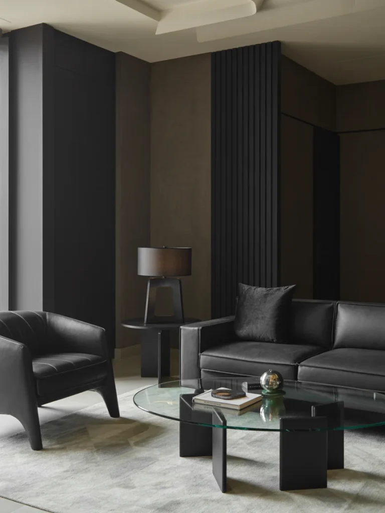 Modern black living room with leather furniture, a glass coffee table, and minimalist decor.